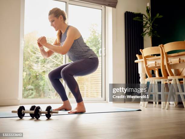 active woman practicing squats at home - agachar se imagens e fotografias de stock
