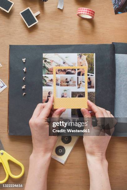 woman holding frame over photo on scrapbook - diy craft stock pictures, royalty-free photos & images