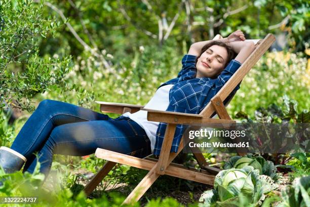 young woman sleeping on chair in organic vegetable garden - deck chair stock pictures, royalty-free photos & images