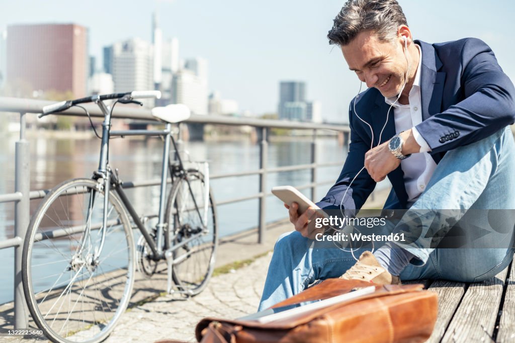 Businessman smiling at video call through mobile phone while sitting on bench