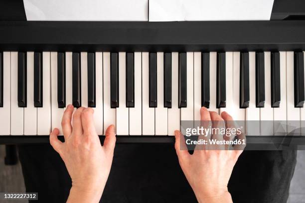 mid adult woman playing piano notes at home - piano stock pictures, royalty-free photos & images