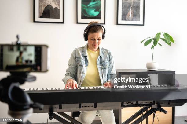 mid adult woman filming while playing piano at home - pianist front stock pictures, royalty-free photos & images