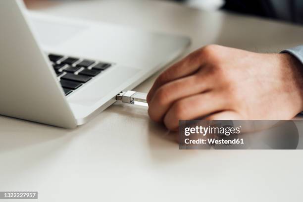 businessman putting pen drive in laptop on desk - usb stick stock-fotos und bilder