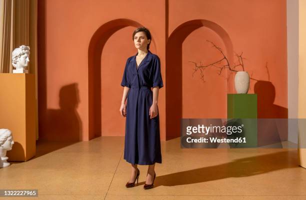 young woman standing in front of orange wall - art gallery people stock pictures, royalty-free photos & images