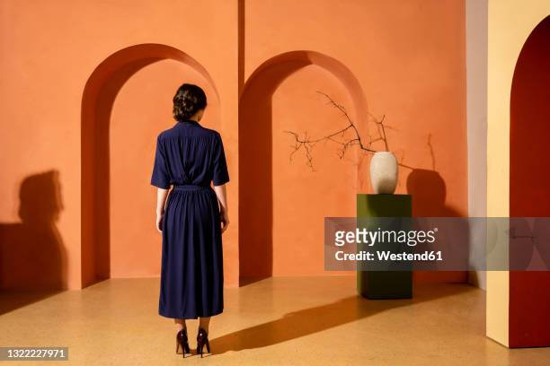 woman standing in front of orange wall with arches - vintage dress imagens e fotografias de stock