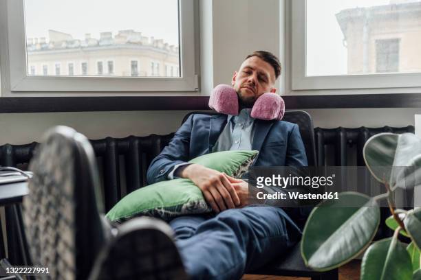 businessman with neck pillow relaxing on chair in office - nackstöd bildbanksfoton och bilder