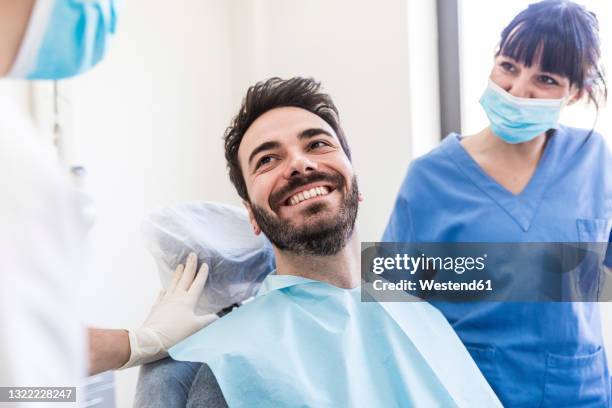 smiling male patient with female dentists at medical clinic - tandarts stockfoto's en -beelden