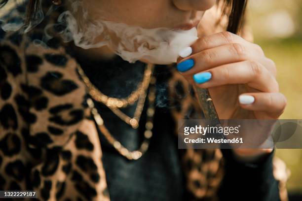 woman smoking marijuana cigarette outdoors - joint body part stock-fotos und bilder