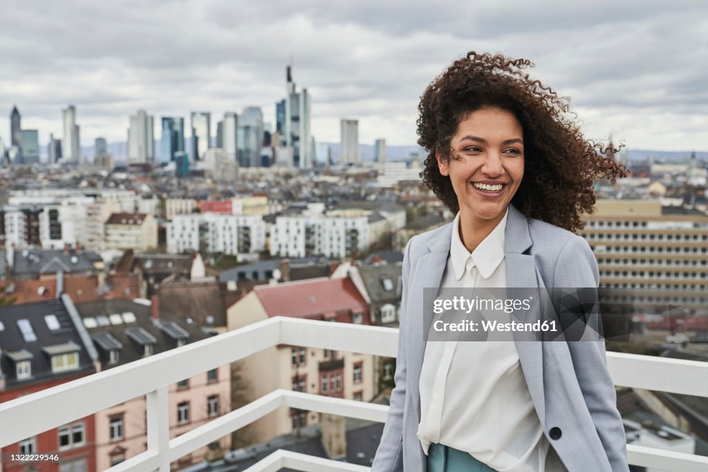 Smiling female entrepreneur on rooftop in city
