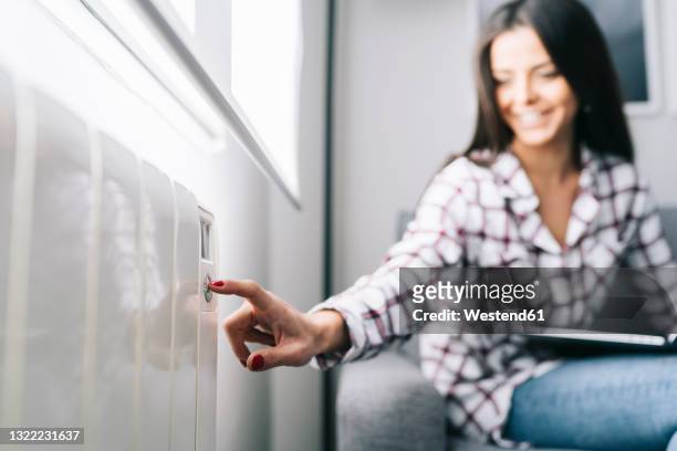 young woman touching heating push button at home - hot spanish women ストックフォトと画像