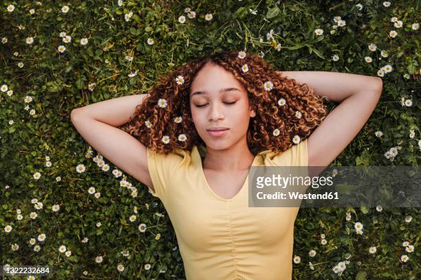 young woman with hands behind head relaxing on meadow - wearing flowers stock pictures, royalty-free photos & images