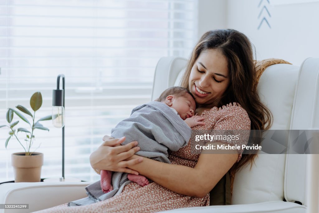 Mother holding her baby boy in the nursery room