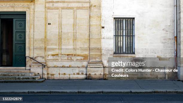 old stone facade, wooden door and empty street in paris - european outdoor urban walls stockfoto's en -beelden