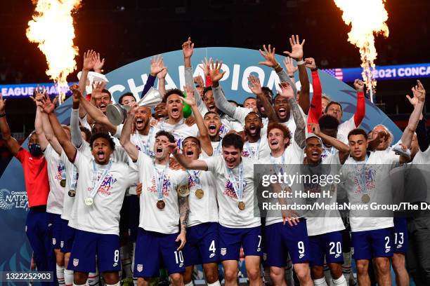 United States players celebrate their win over Mexico as forward Christian Pulisic, holds up the CONCACAF Nations League Championship trophy after...