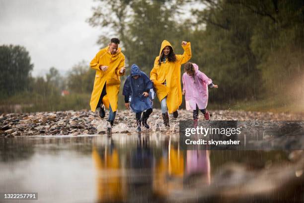 zorgeloos gezin dat pret heeft terwijl het lopen in water tijdens regenachtige dag. - mother son shower stockfoto's en -beelden