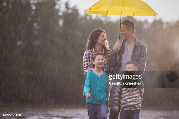 glückliche familie im gespräch beim spazierengehen auf einem regen in der natur. - mother protecting from rain stock-fotos und bilder