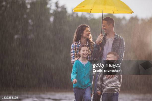 bonne famille parlant en marchant sur une pluie dans la nature. - se protéger de la pluie photos et images de collection