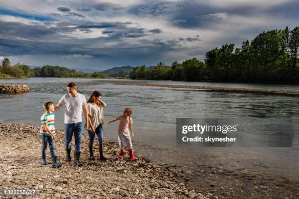 happy family talking while walking on the riverbank. - riverbank stock pictures, royalty-free photos & images