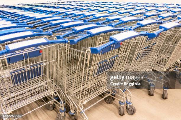 many supermarket shopping carts parked together - shopping trolleys stockfoto's en -beelden