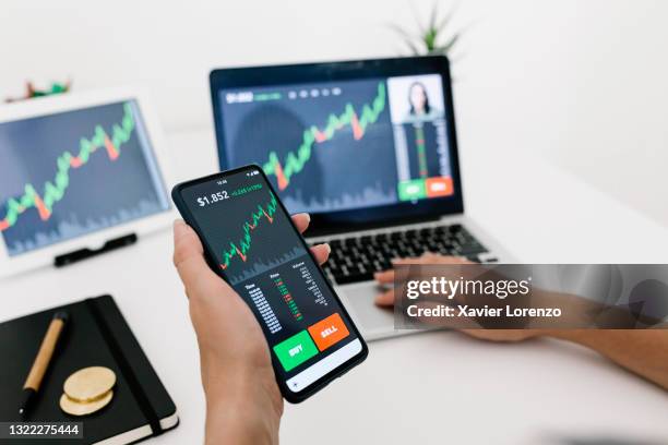 close-up of businesswoman working on stock market on mobile phone app and laptop at home - aktenmappe stock-fotos und bilder