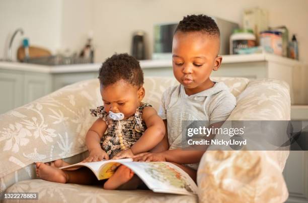 siblings die de onderwijsboeken van kinderen thuis letten - brother toddler sister stockfoto's en -beelden