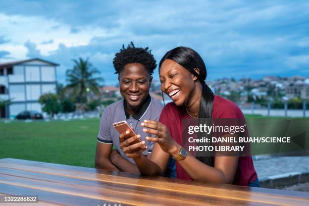 laughing friends looking at a smartphone - ghana africa - fotografias e filmes do acervo