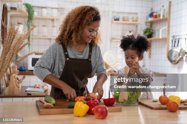 mother and daughter having fun with the vegetables. - jamaicaanse etniciteit stockfoto's en -beelden