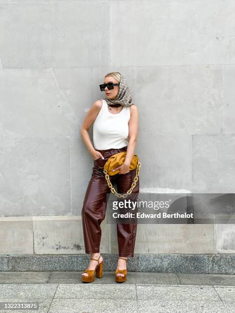 Justyna Czerniak wears a white tank top from In Wear, brow leather crocodile pattern pants from Samsoe Samsoe, a pale brown pouch leather bag with a...