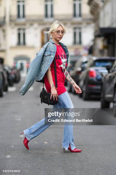 Emy Venturini wears clear sunglasses from Prada, a blue denim jacket from Balenciaga, a red long oversized t-shirt with a printed star and a slogan...