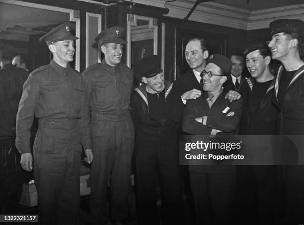 English actors John Gielgud and Arthur Askey , in centre, with members of the audience in uniform backstage after a special performance for British...