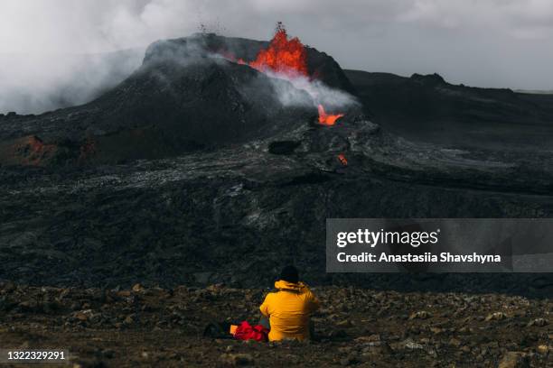 hombre viajero sintiendo asombro mirando la erupción volcánica fagradalsfjall en islandia - volcanic activity fotografías e imágenes de stock