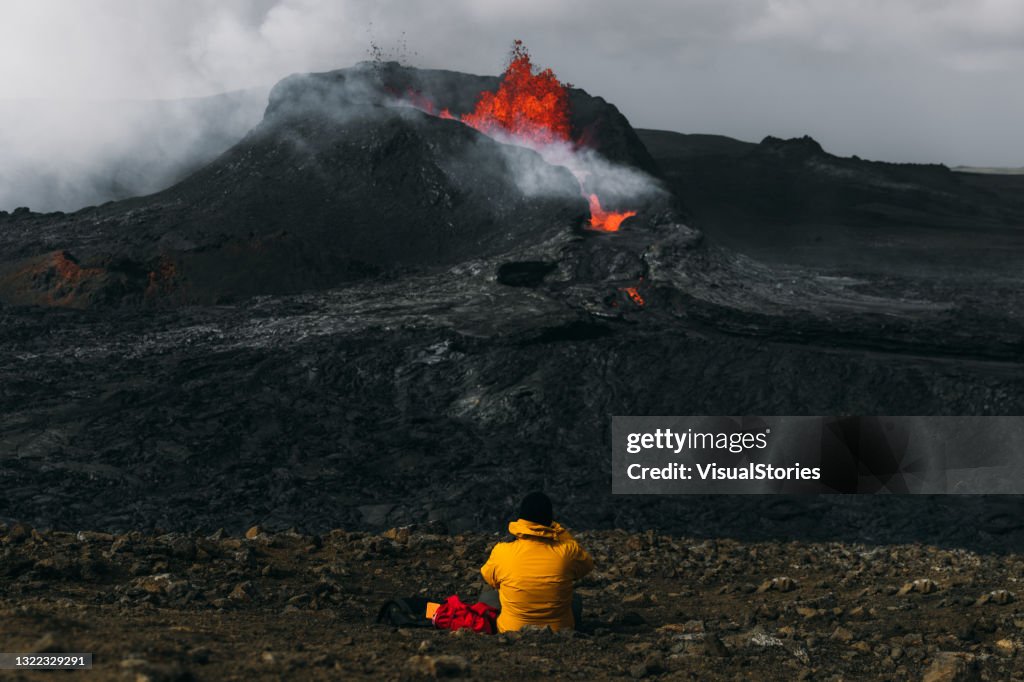Man traveler feeling awe looking at Fagradalsfjall volcanic eruption in Iceland