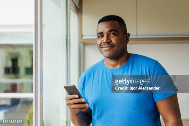 ritratto di un uomo che tiene lo smartphone a casa - blu chiaro foto e immagini stock