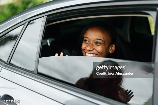 femme faisant signe à son ami depuis la fenêtre de la voiture - woman waving goodbye photos et images de collection