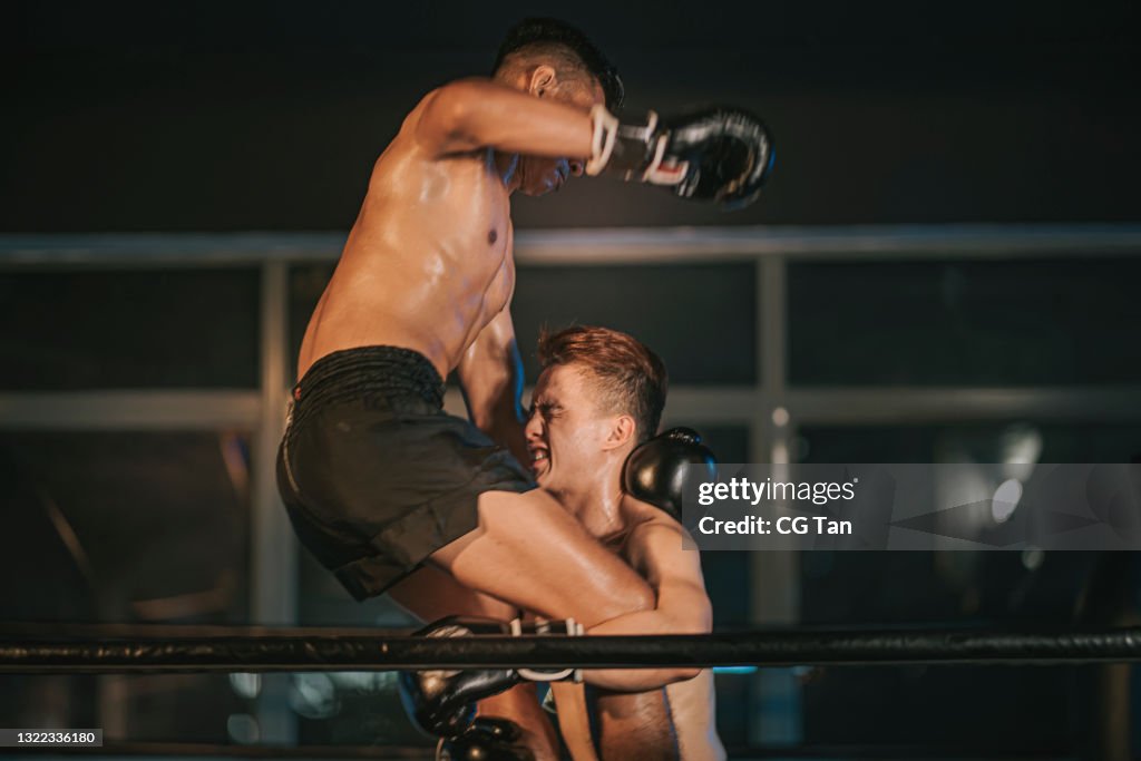 Muay Thai boxer body climb jump downward elbow strike in boxing ring match knock down opponent