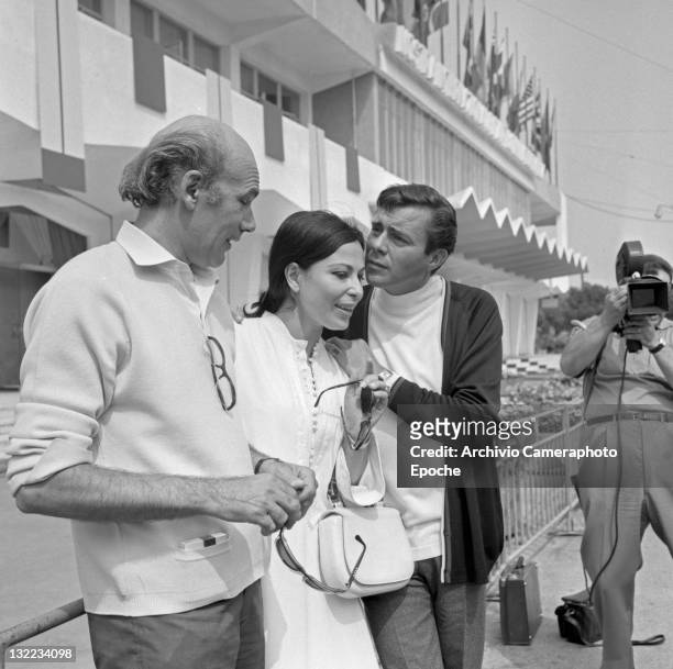 English actor Dirk Bogarde with movie director Jack Clayton and Israeli actress Haya Harareet outside the Movie Festival palace, Lido, Venice 1967.