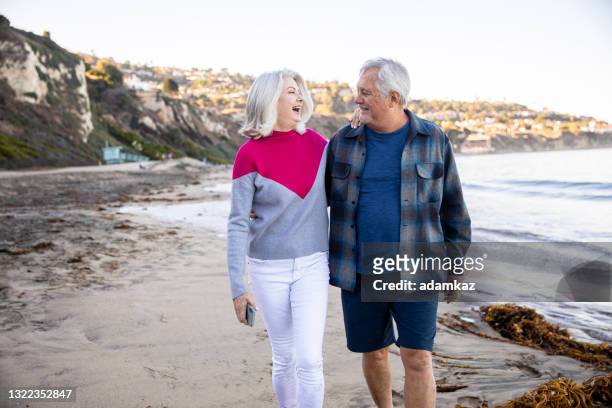 couple senior marchant le long de la plage - fat guy on beach photos et images de collection