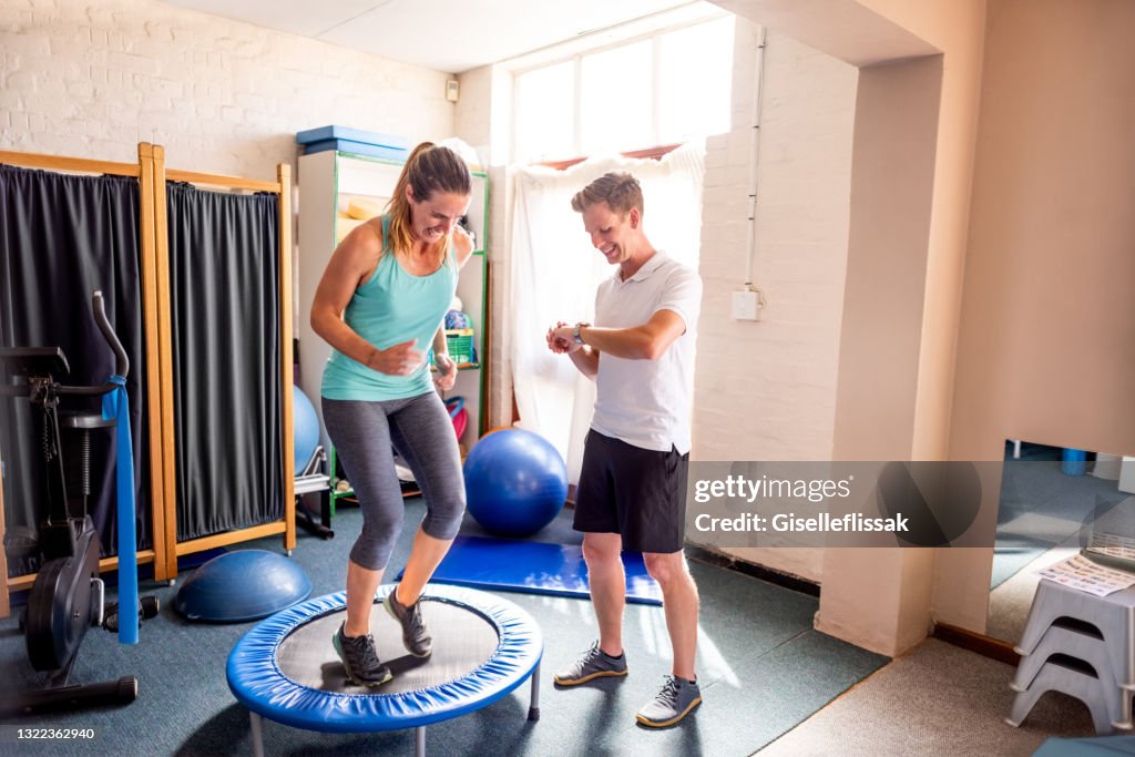 Mujer haciendo ejercicio en trampolín con fisioterapeuta en rehabilitación