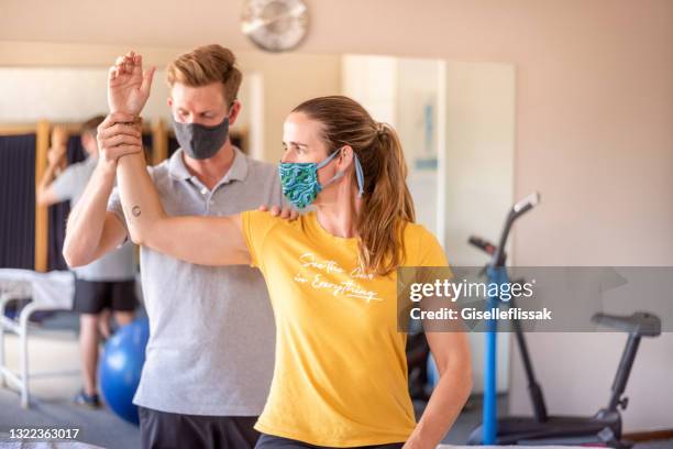 physical therapist examining arm of a woman at rehab - physiotherapy shoulder stock pictures, royalty-free photos & images