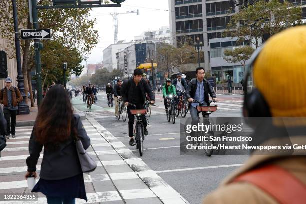Bicyclists ride along Market Street as pedestrians cross 9th Street on Tuesday, October 15, 2019 in San Francisco, Calif.