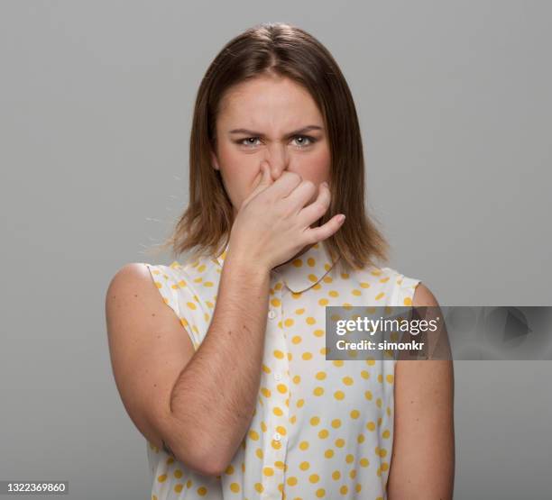 close-up of young woman holding nose - unpleasant smell stock pictures, royalty-free photos & images