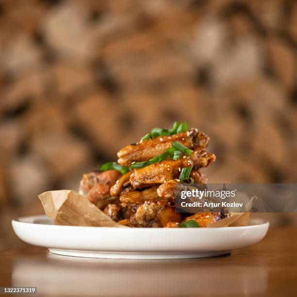 appetizing roasted or fried chicken wings sesame seeds and onion. soft focus. food concept. square format or 1x1 for posting on social media. side view. copy space on top of image - plate side view stock pictures, royalty-free photos & images