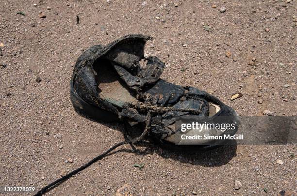 rotting black shoe disintergrating on a sandy shore - ugly shoes - fotografias e filmes do acervo