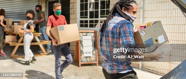 community volunteers in masks receiving donations of food and clothing - humanitarian aid 個照片及圖片檔