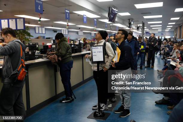 Elias Dubaie of San Francisco and Kahlai Pratt of San Francisco watch a sign board while they wait in line to apply for the Real ID at the DMV on...