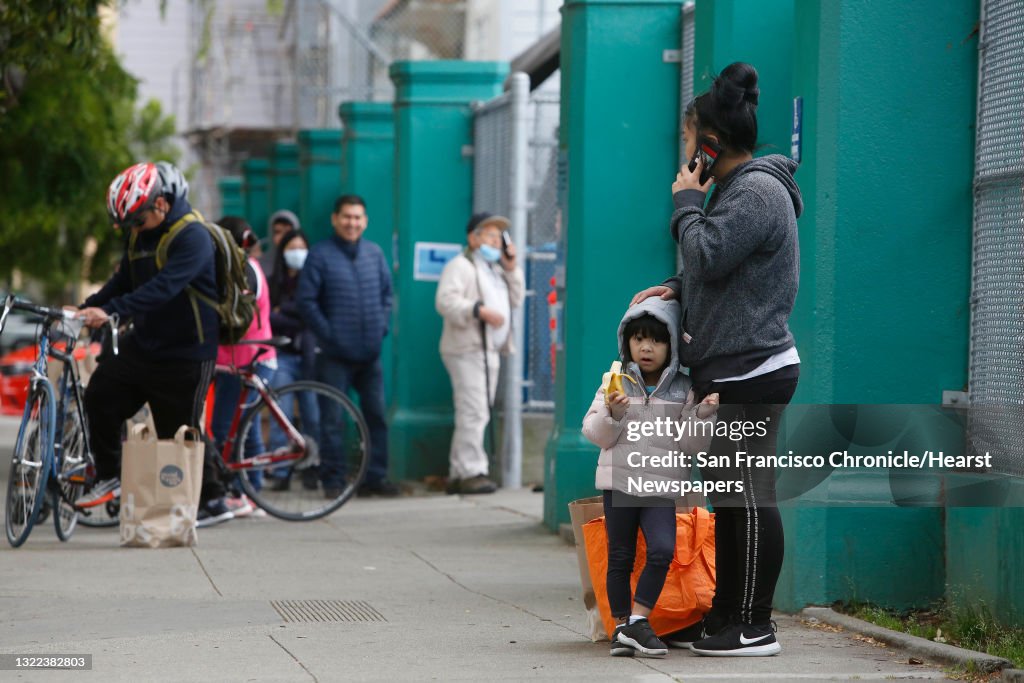 Keirah Novenario, 3, enjoys a banana as she stands with her mother Kelly Ajoste, both of San Francisco, after they visited the San Francisco-Marin Food Bank pop up food pantry at Cesar Chavez Elementary school on Tuesday, March 24, 2020 in San Francisco,