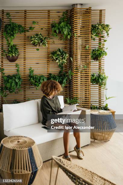 junge frau mit laptop in nachhaltigem haus - vertical garden stock-fotos und bilder