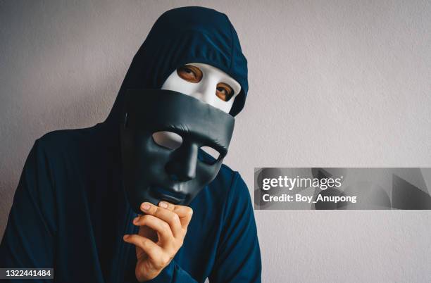 portrait of mystery man wearing hood and hacker mask. - theatermaske stock-fotos und bilder