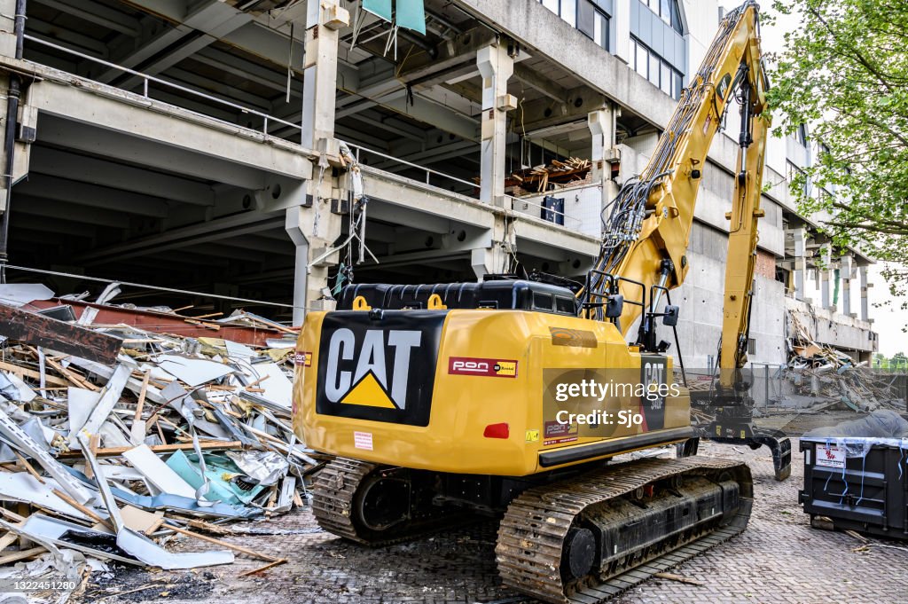 Crawler Excavator machine on a demolition site of an old office building with parts ready for recycling