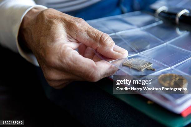 uk, east sussex, close-up of senior mans hand holding coin album - coin collection stock pictures, royalty-free photos & images